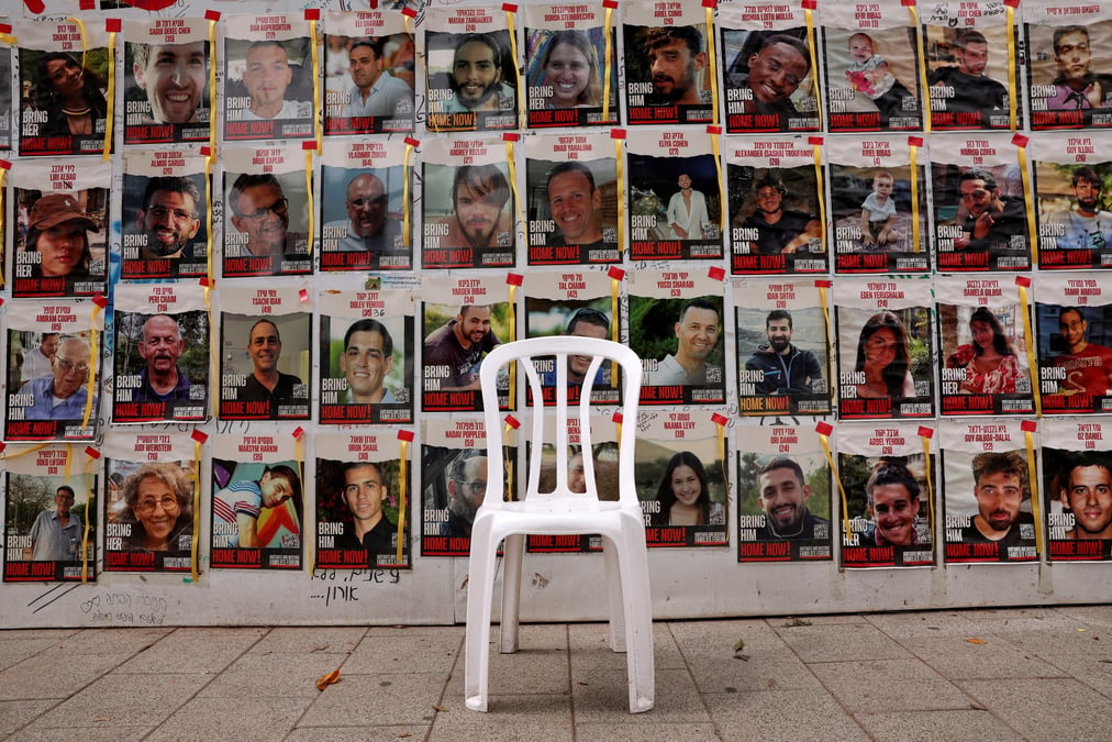 Une chaise est laissee devant des affiches avec des photos d'otages