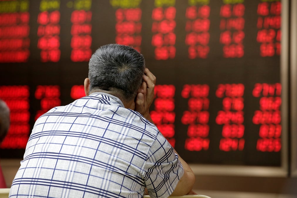 Photo d'un homme regardant un tableau electronique affichant des informations sur les actions a pekin