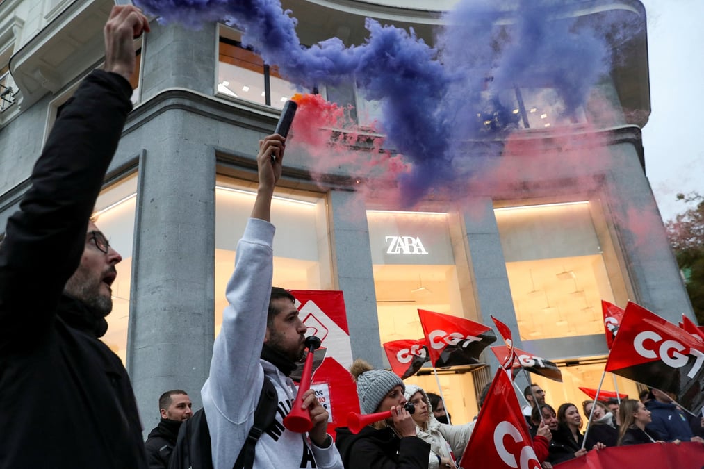 Des personnes tiennent des drapeaux du syndicat espagnol cgt lors d'une manifestation devant un magasin de vetements zara a madrid