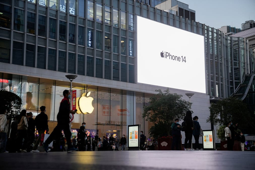 People walk near a display advertising the apple iphone 14 outside its store in shanghai