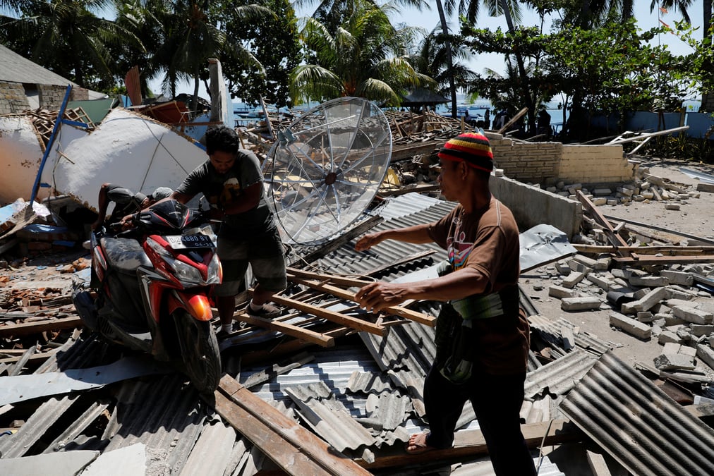 Villagers push a motorcycle on debris after an earthquake hit lombok island in pemenang