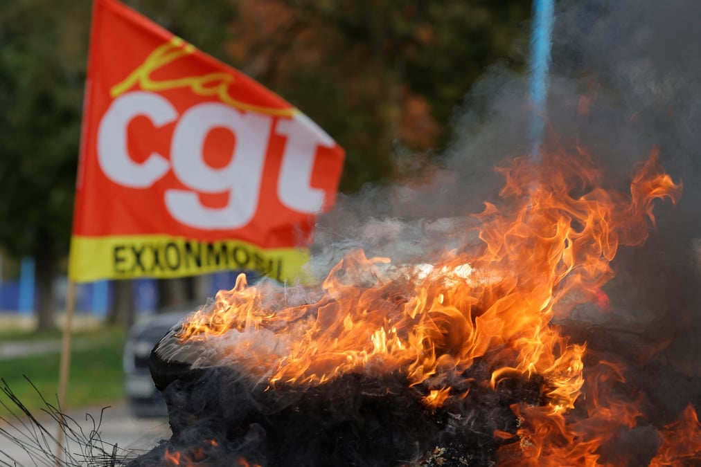 Un drapeau du syndicat cgt et des pneus enflammes devant la raffinerie de petrole exxonmobil