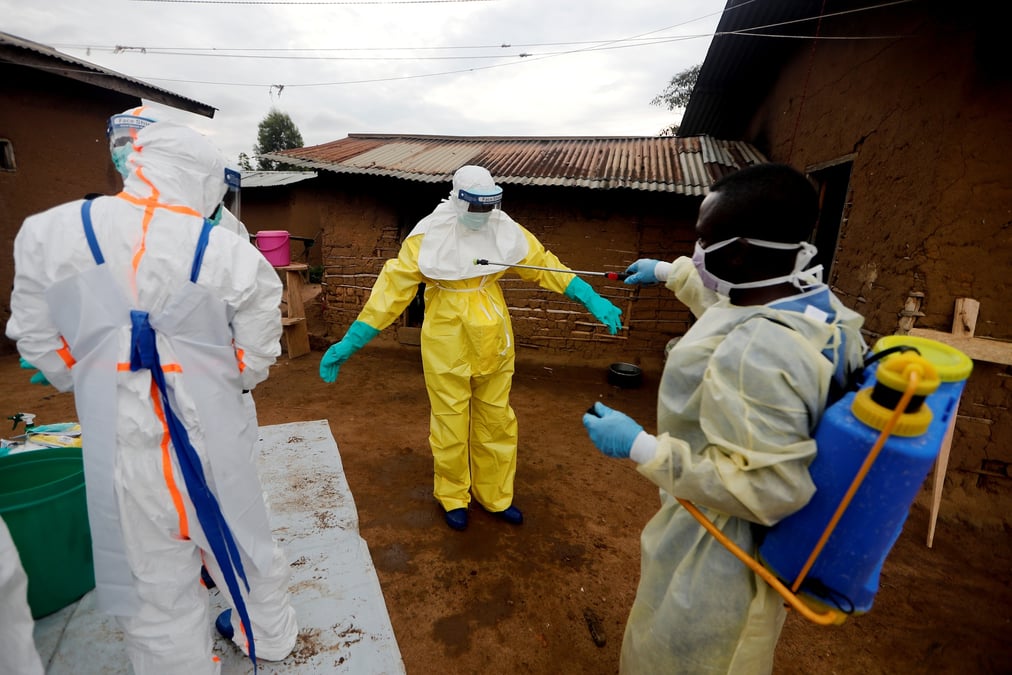 Un travailleur de la sante decontamine son collegue apres etre entre dans la maison d'une femme soupconnee d'avoir decede de la fievre ebola