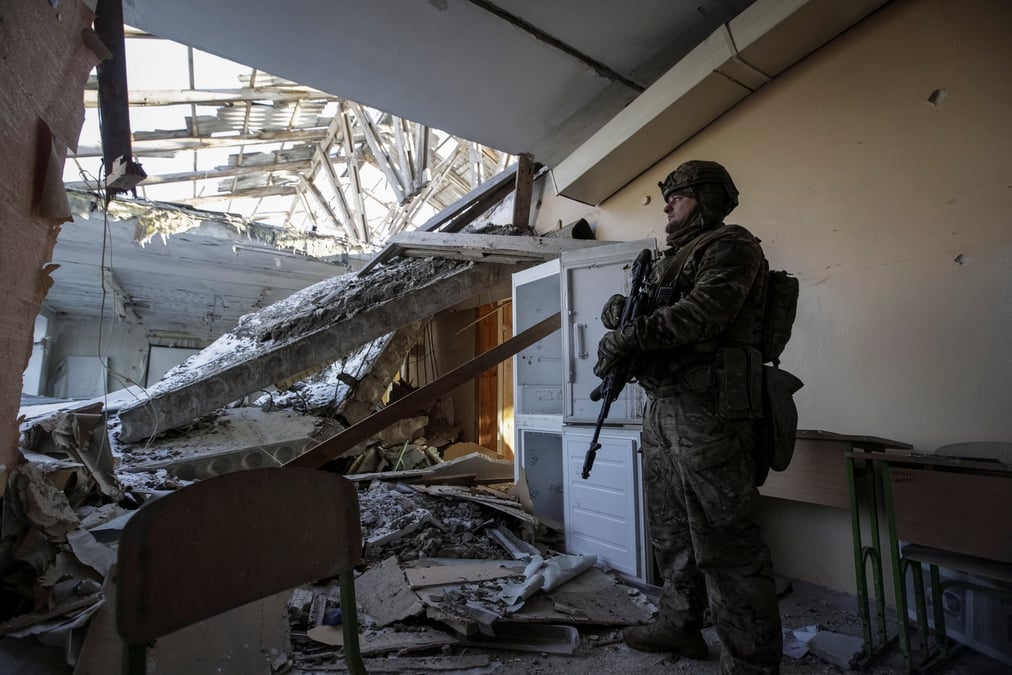 Un militaire ukrainien dans une ecole detruite