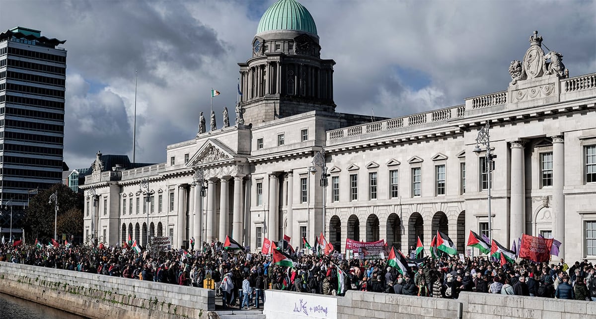 Un grand nombre de manifestants munis de banderoles, de drapeaux et de pancartes défilent dans les rues de Dublin en direction de l'ambassade d'Israël pendant une manifestation, fin 2024.