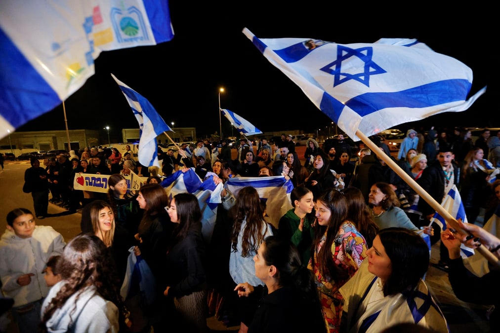 Des personnes brandissent des drapeaux israeliens a ofakim, en israel, apres la liberation des otages captures lors de l'attaque du 7 octobre par le hamas