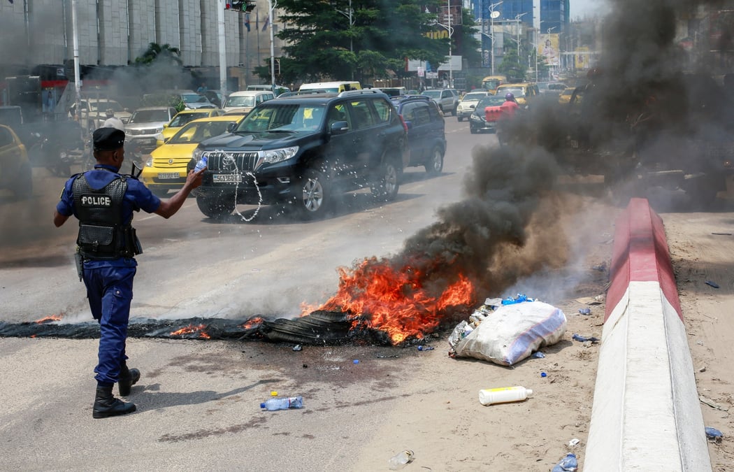 Un policier jette de l'eau sur des pneus en feu apres une manifestation pres de l'ambassade americaine a kinshasa, en rdc