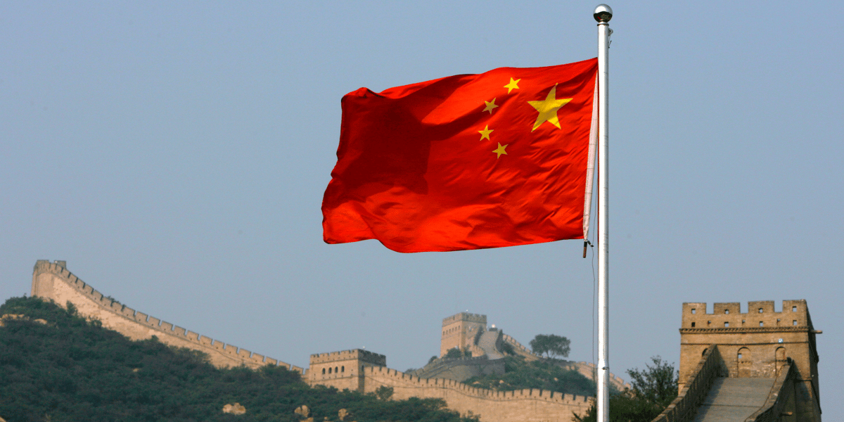 Un drapeau chinois flotte devant la grande muraille de chine, situee au nord de pekin