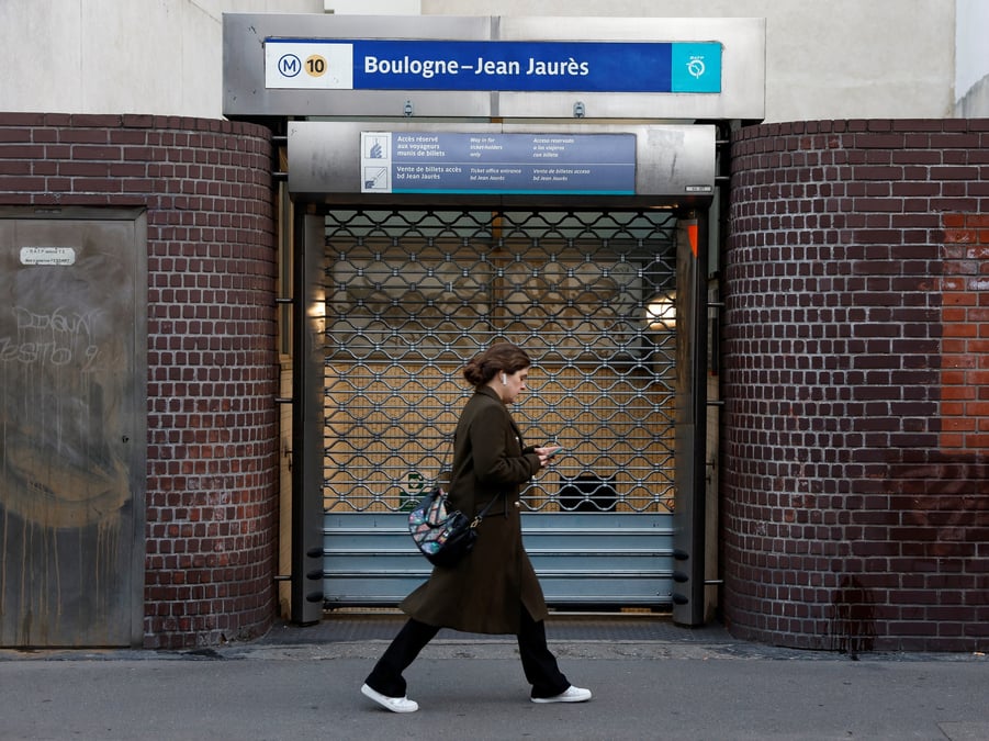 Une femme passe devant la station de metro boulogne-billancourt pendant la journee de greve a la ratp