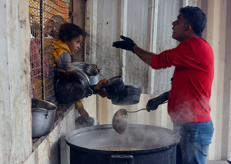 Des palestiniens se rassemblent pour recevoir de la nourriture preparee par une cuisine caritative, a khan younis