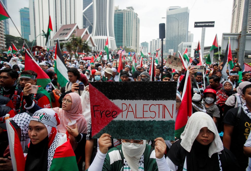 Un manifestant tient une pancarte peinte avec le drapeau palestinien et le slogan "free palestin" lors d'une manifestation a kuala lumpur