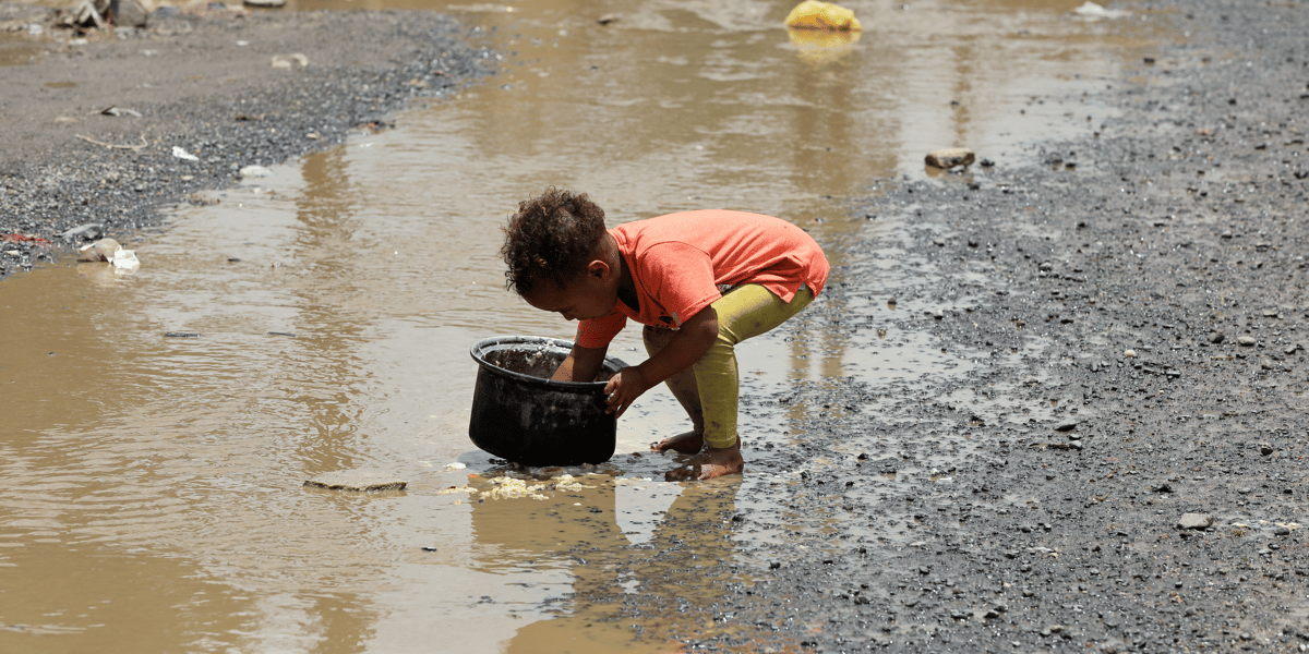 Yémen : un enfant nettoie une marmite avec de l'eau de pluie dans un bidonville de la capitale Sanaa, le 26 juillet 2020