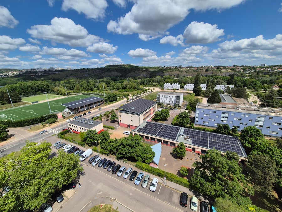 Vue sur le stade de football, et une des écoles équipées de panneaux photovoltaiques dans le quartier à énergie positive de Dijon : La Fontaine d'Ouche
