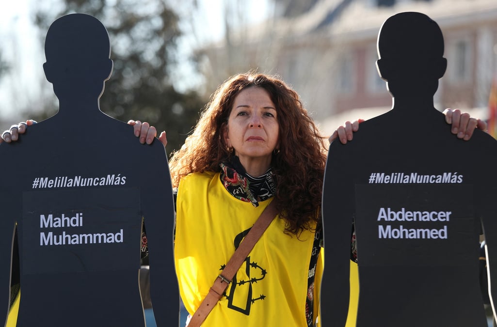 Une femme portant le logo d'amnesty international place des silhouettes et des noms de migrants devant le palais de la moncloa en espagne pour protester contre l'incident de melilla