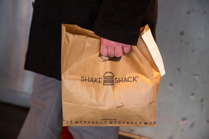 A customer holds a bag full of food inside of a shake shack store in new york