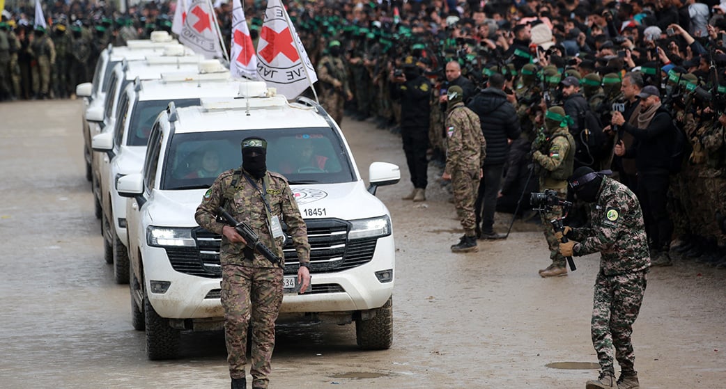 Un palestinien du Hamas précède des véhicules de la Croix-Rouge internationale (CICR) qui arrivent à Nuseirat, pour accueillir trois otages israéliens dans le cadre du septième échange d'otages et de prisonniers, le 22 février 2025.
