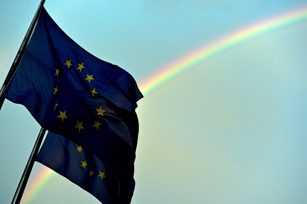 Un arc-en-ciel est visible derriere les drapeaux europeens
