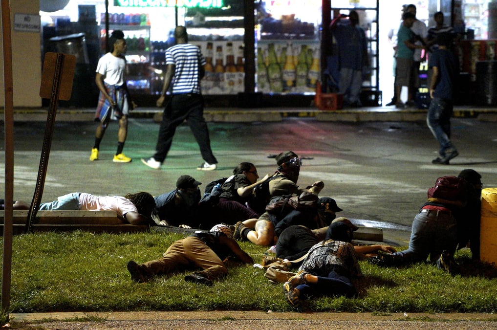 Protesters fall to the ground to take cover after shots were fired in a police-officer involved shooting in ferguson