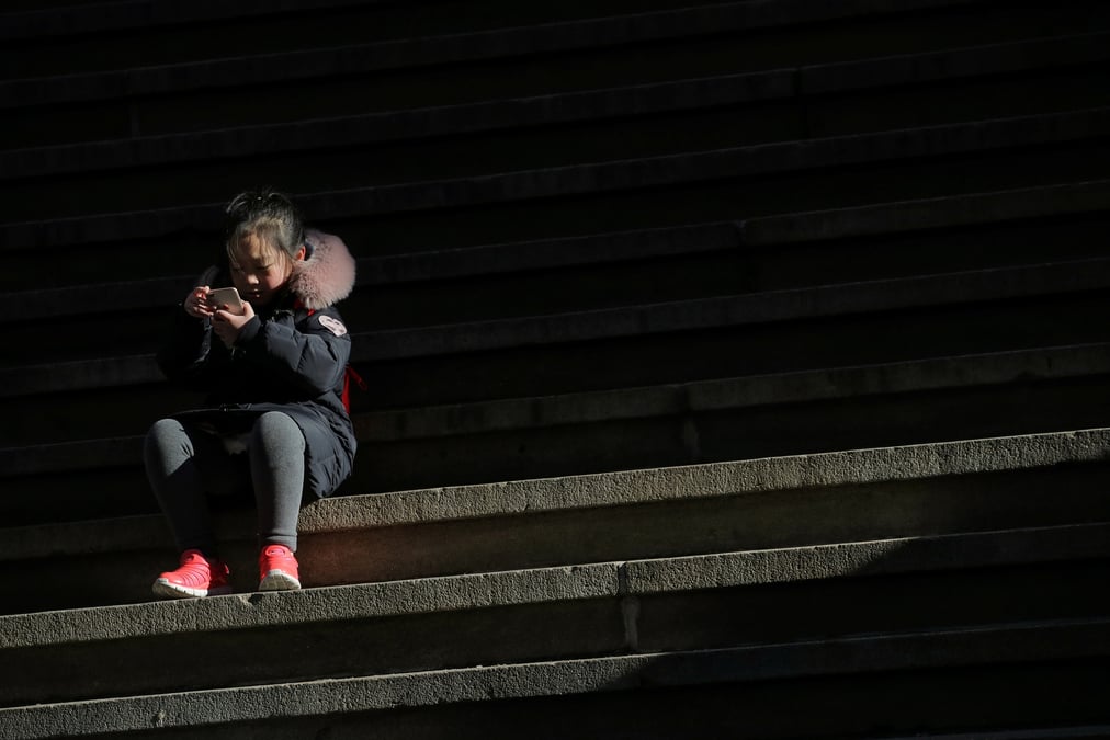 A child uses a smartphone on wall st. during the morning commute in new york