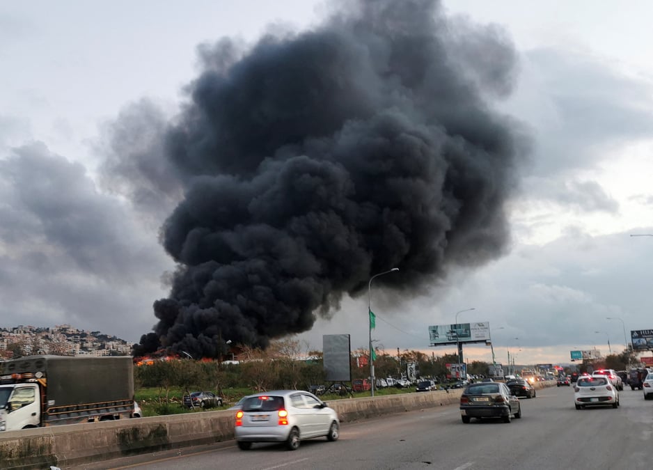 Des vehicules roulent alors que de la fumee s'eleve d'un site touche par une frappe aerienne pres de la ville de ghaziyeh, au liban