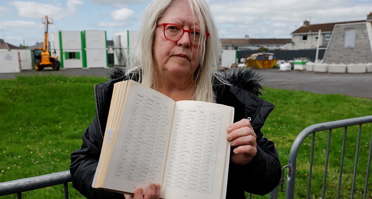 Anna Corrigan, 69 ans, dont les deux frères seraient morts à Thuam, montre un registre des victimes.