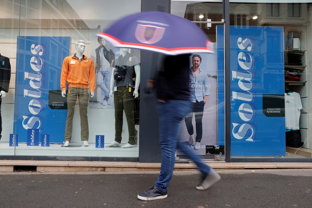 Un homme passe devant une boutique de vetements a cambrai