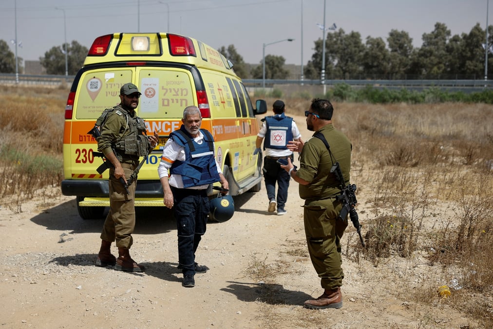 Des soldats israeliens et des medecins marchent pres d'une ambulance apres que le groupe islamiste palestinien hamas a revendique une attaque au point de passage de karem shalom, pres de la frontiere israelienne avec gaza