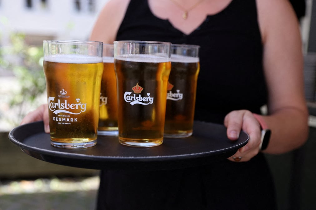Un employe de bar porte un plateau de biere carlsberg a copenhague.