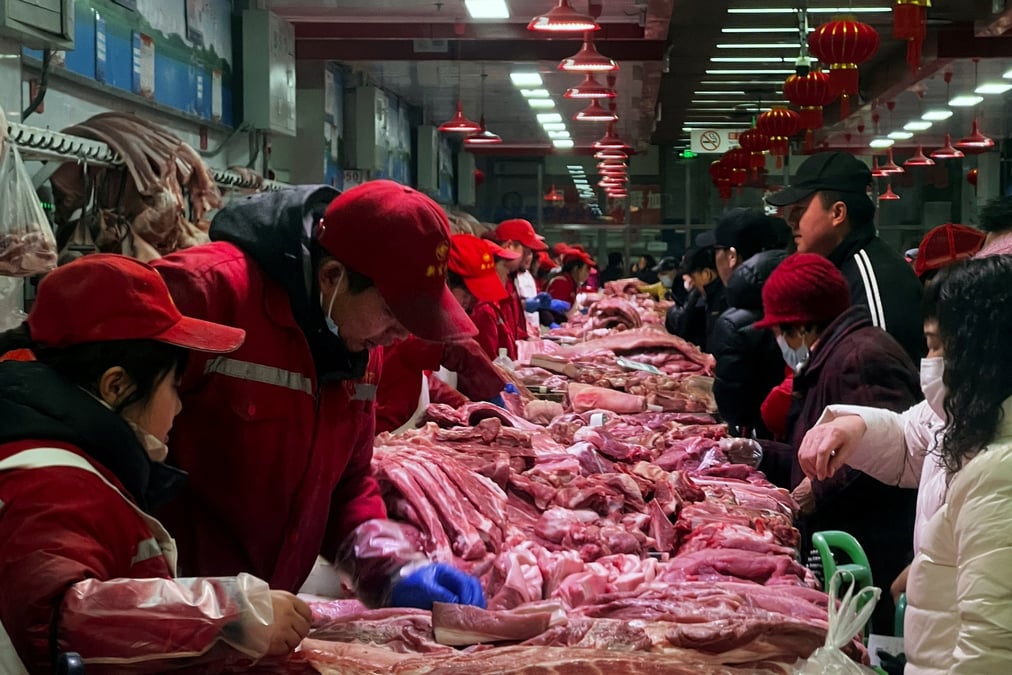Des vendeurs de porc s'occupent des clients dans un marche a pekin