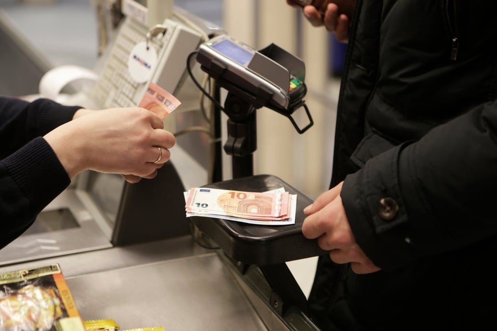 Une caissiere compte des billets dans un magasin