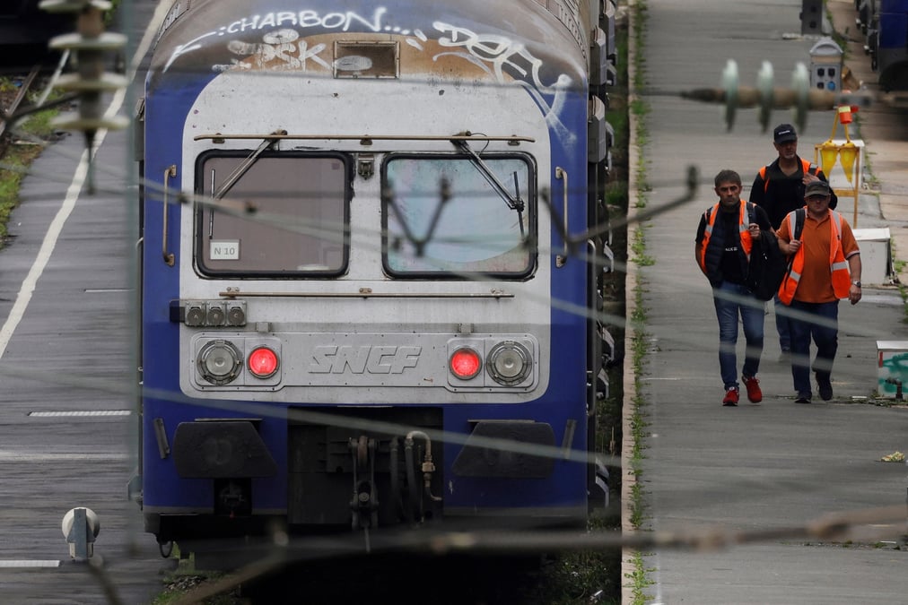 Des ouvriers passent devant des trains regionaux ter au depot sncf d'hellemmes-lille
