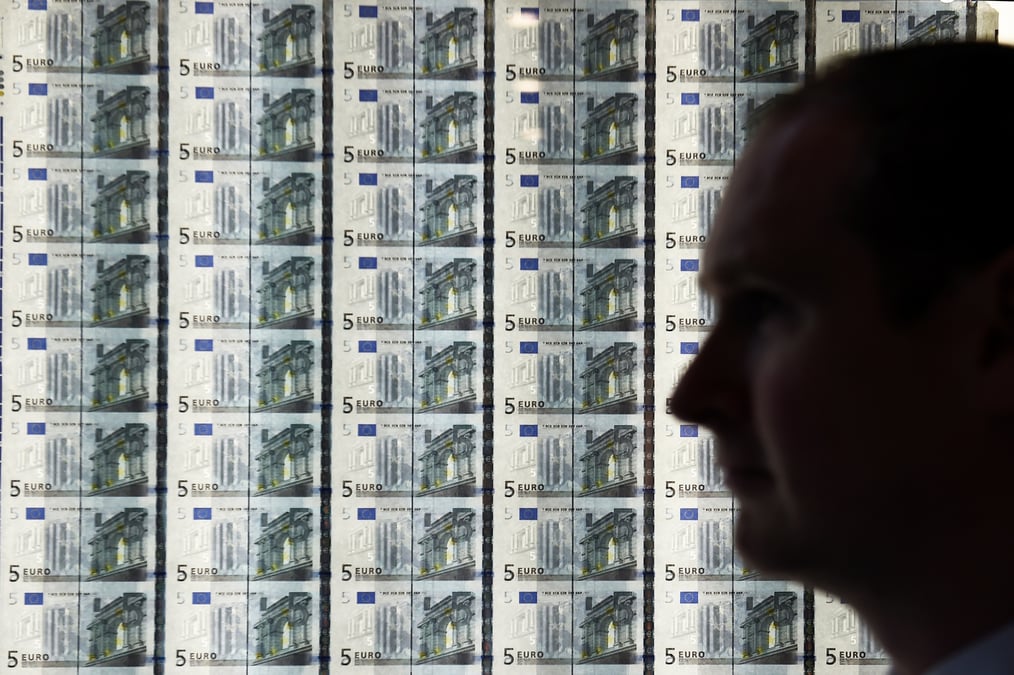 Un homme est vu devant une feuille de billets de cinq euros