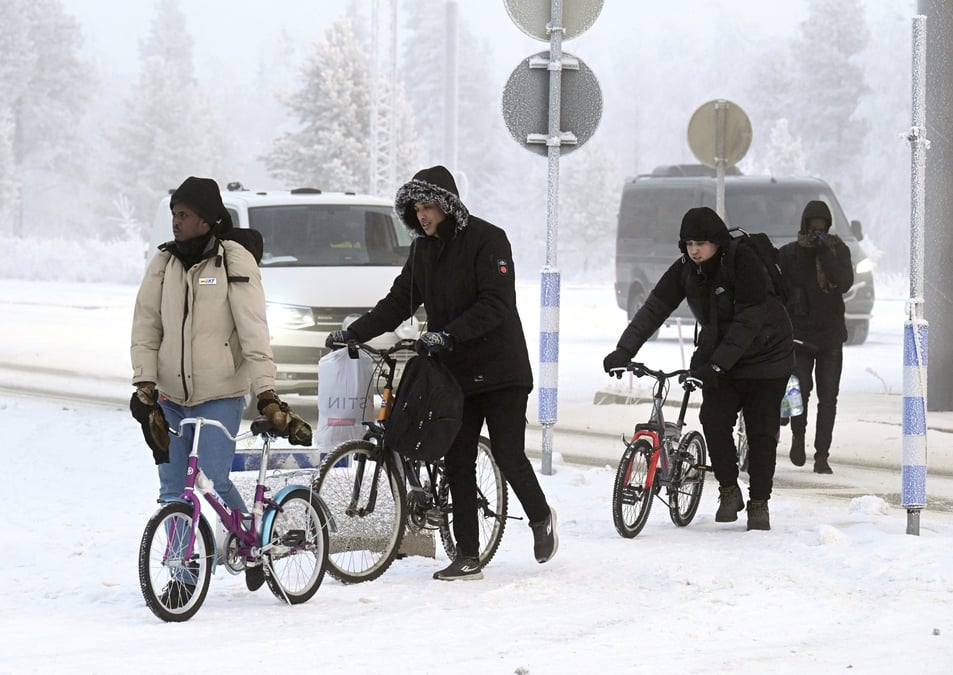 Des migrants marchent avec des velos au poste frontiere entre la finlande et la russie, a salla