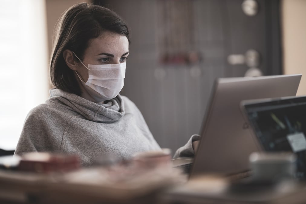 Femme avec un masque devant son ordinateur