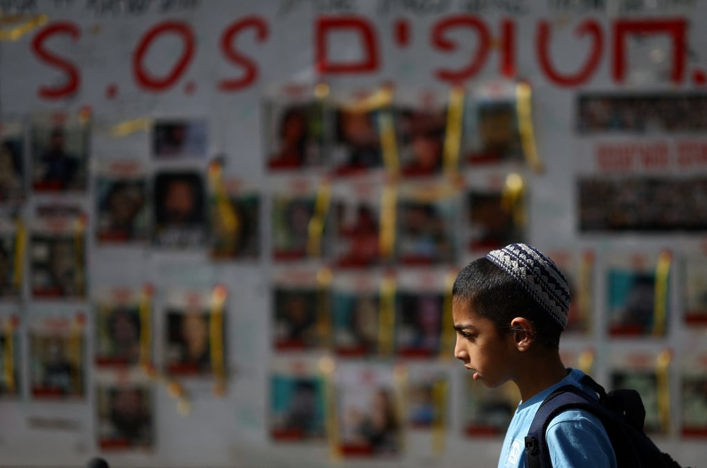 Des personnes passent devant des affiches montrant des photos d'otages enleves lors de l'attaque du 7 octobre par le hamas, a tel aviv