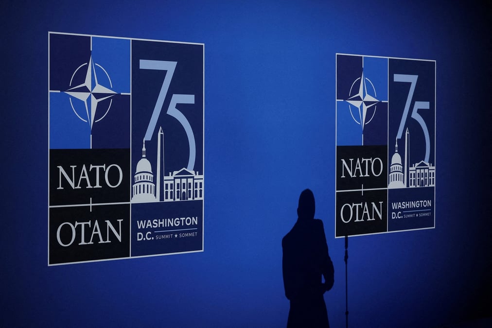 L'ombre d'un journaliste se dessine a cote des logos lors de l'evenement de celebration du 75eme anniversaire de l'otan a washington