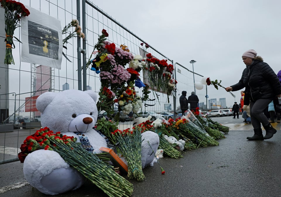 Une femme depose des fleurs sur un memorial improvise en l'honneur des victimes d'un attentat a la salle de concert crocus city hall, dans la banlieue de moscou