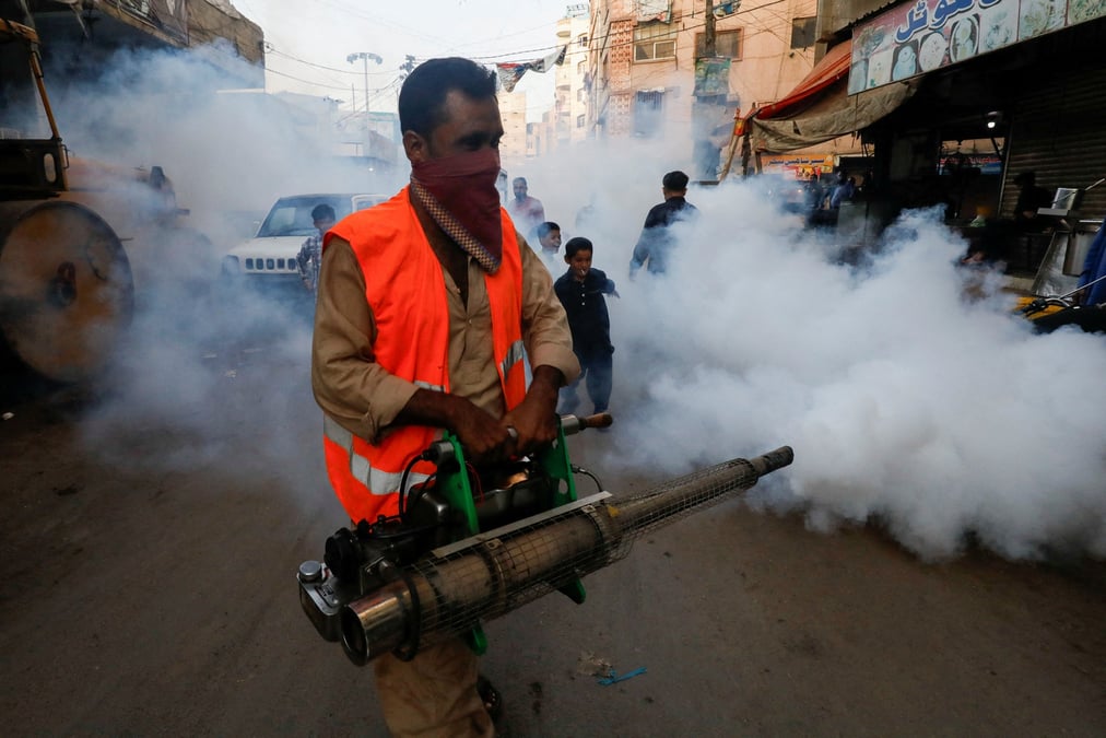Un homme vaporise un insecticide dans une rue de karachi, au pakistan