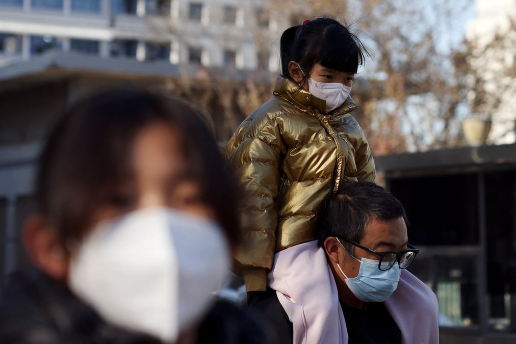 Un homme porte un enfant devant un hopital, en chine