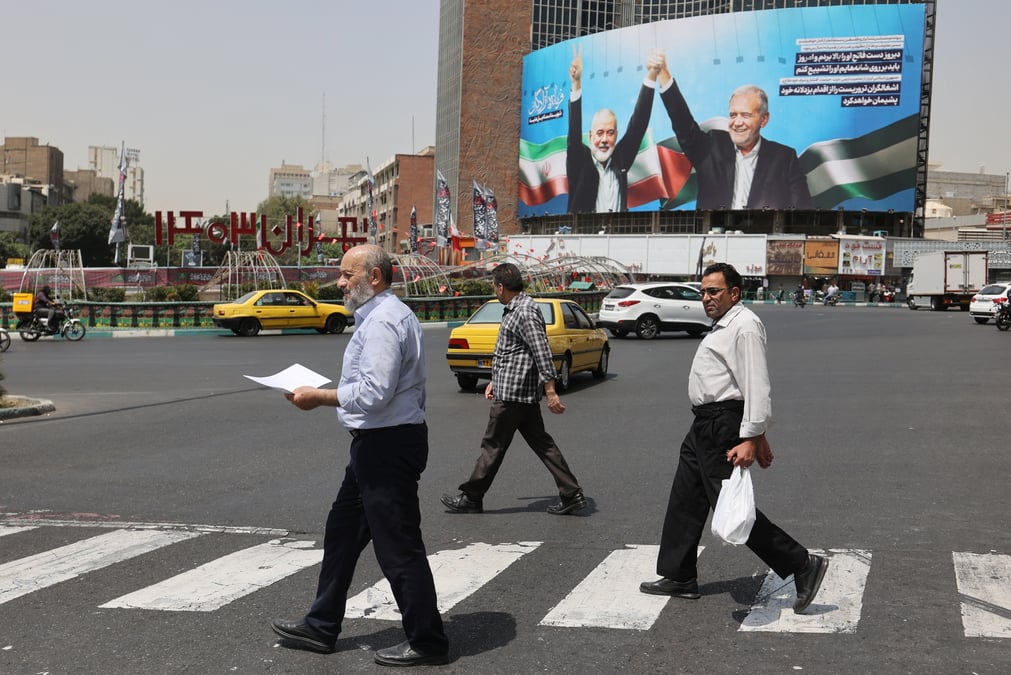 Des passants devant une photo du chef du hamas assassine, ismail haniyeh, et du president iranien, masoud pezeshkian, a teheran, en iran