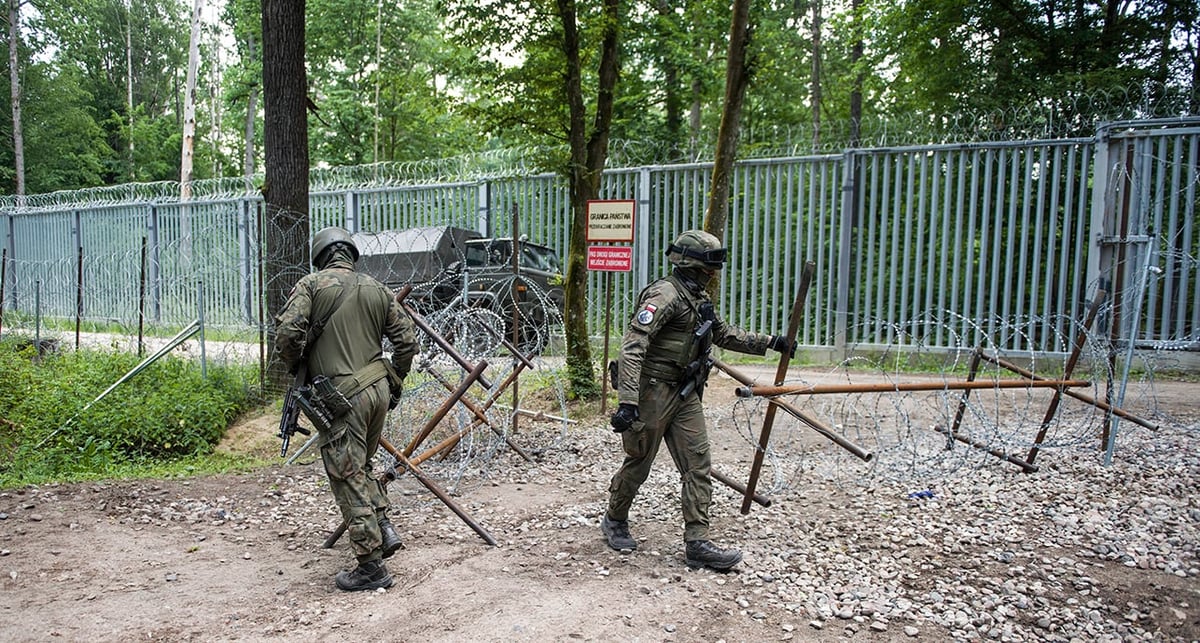 Des soldats polonais patrouillent à la frontière avec la Biélorussie le long de la clôture frontalière dans la forêt de Bialowieza.