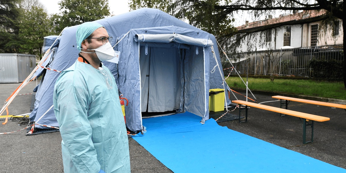 Coronavirus/Covid-19 : Un soignant portant un masque attend devant un checkpoint médical en Italie