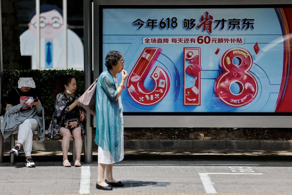 Des personnes attendent le bus pres d'un panneau publicitaire de jd.com pour le festival du shopping "618", a pekin