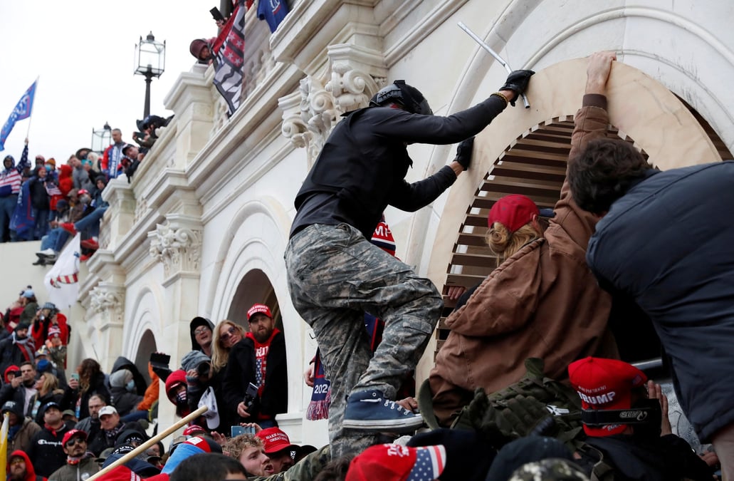 Des manifestants pro-trump escaladent un mur alors qu'ils prennent d'assaut le capitole des etats-unis