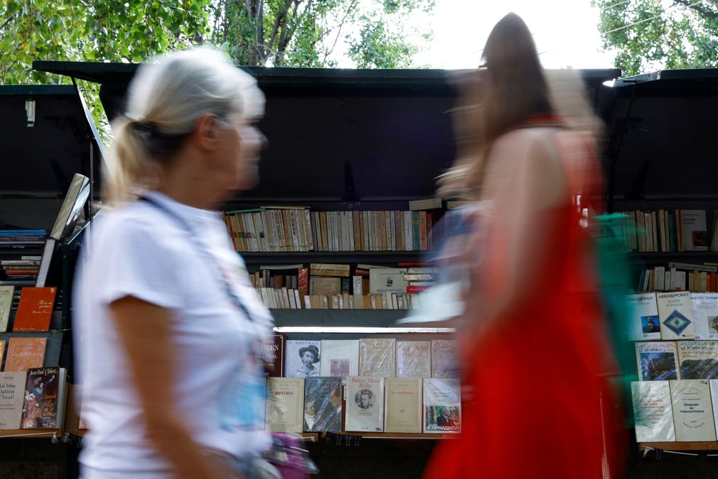 Des personnes passent devant des bouquinistes sur les quais de la seine a paris
