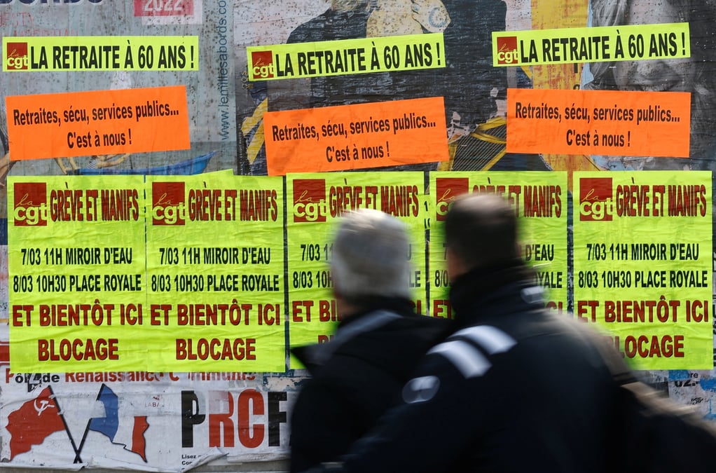 Des gens passent devant des affiches a bouguenais appelant a la greve et a des manifestations contre le plan de reforme des retraites du gouvernement
