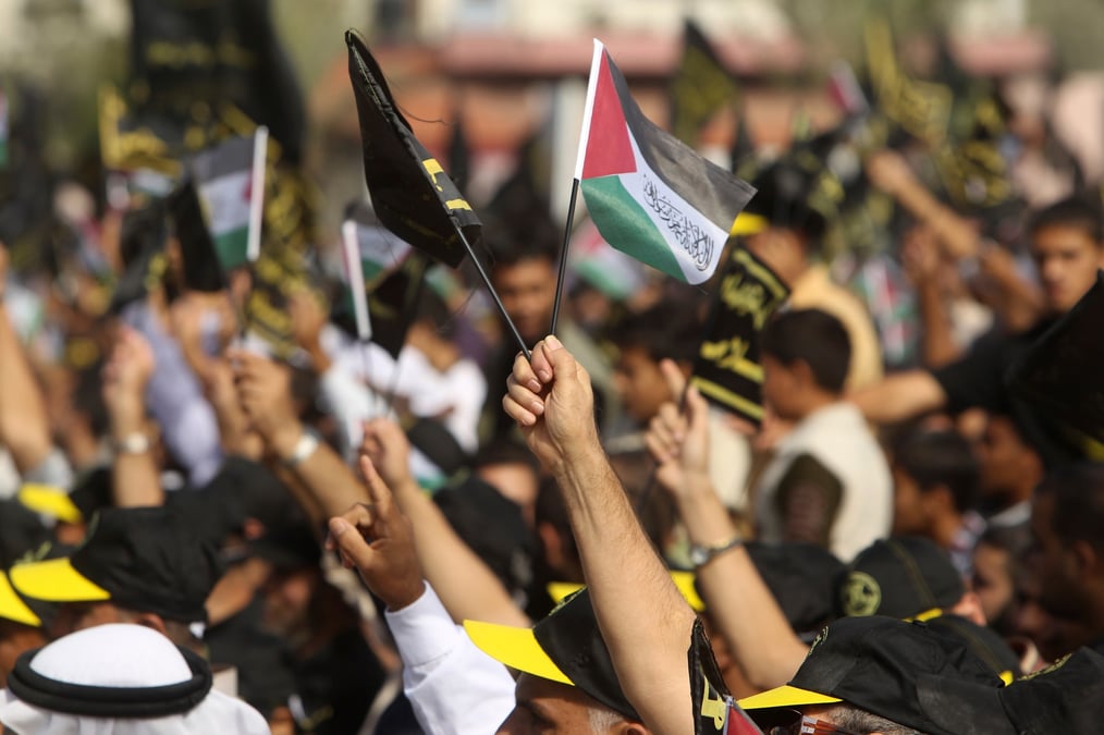 Un palestinien brandit des drapeaux palestiniens et du jihad islamique lors d'un rassemblement a gaza