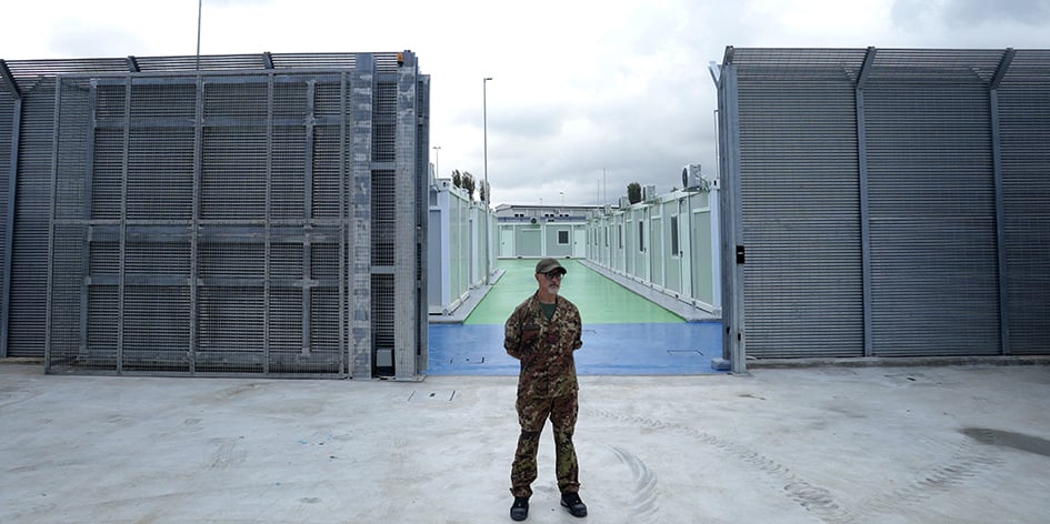 Un officier de police italien se tient dans un centre pour migrants récemment construit par l'Italie dans le port de Shengjin, à quelque 60 km au nord-ouest de Tirana, le 11 octobre 2024.