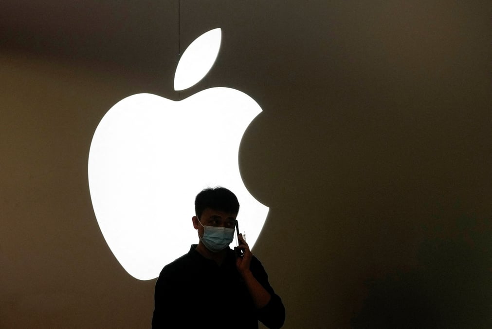 Un homme parle au telephone devant le logo d'apple a l'exterieur d'un magasin a shanghai