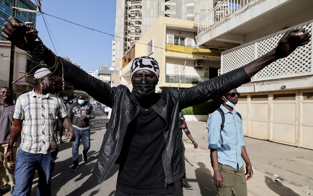 Photo de manifestants senegalais qui marchent apres avoir ete repousses par la police anti-emeute alors qu'ils tentaient de se rassembler pour protester contre le report de l'election presidentielle